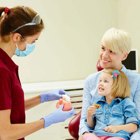 Nurse explaining to a young child how to develop healthy habits of good oral hygiene.