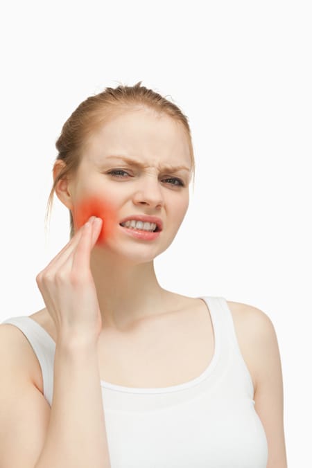 Woman holding her cheek experiencing pain and swelling.