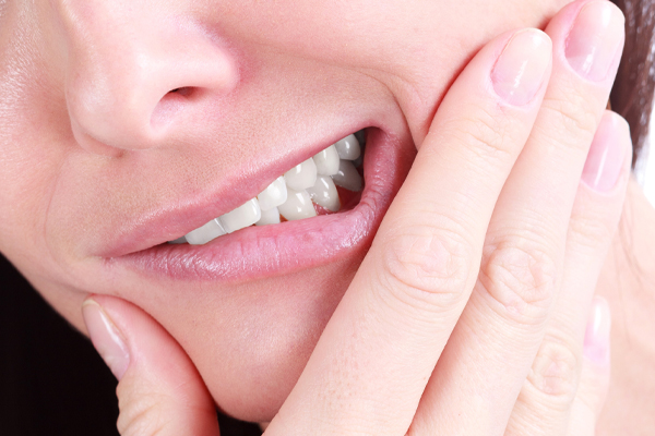 woman holding jaw in pain